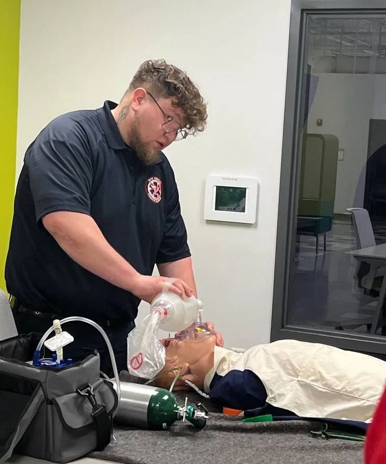 EMTS EMT-Basic student ventilating a training manikin with a bag-valve mask and oxygen